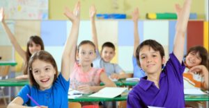 elementary-school-students-raising-hands-in-classroom