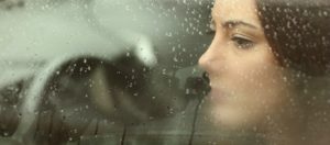 Sad woman looking through a car window